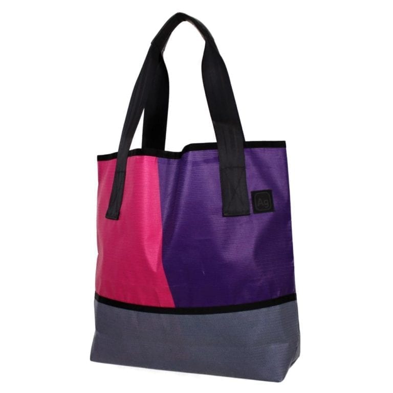 Large tote bag made of upcycled advertising banners from Alchemy Goods; shown with purple and pink fabric