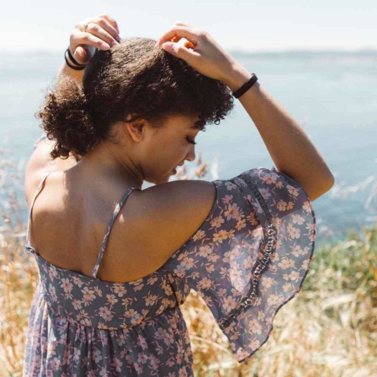 African American female wearing three black Kooshoo brand plastic-free organic hair ties around her wrists.