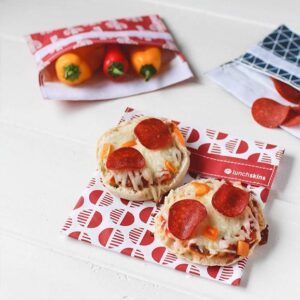 Lunchskins brand reusable food bags shown holding peppers and pizza snacks