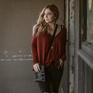 Woman modeling Alchemy Goods slim cross body purse made with upcycled materials