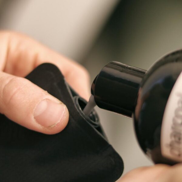 Close up view of shampoo being poured into eco friendly Matador brand black FlatPak reusable toiletry bottle.