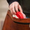 Earth friendly Pokito brand red and white pocket sized cup collapsed to pocket size and placing into leather bag.