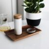 Soma brand eco friendly pearl white insulated ceramic travel mug with bamboo cap displayed on white counter top with loose leaf tea.