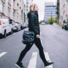 Female shown crossing city street with her crossbody shoulder bag by Alchemy Goods.