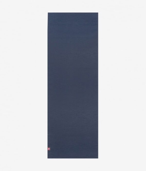 Manduka brand natural rubber 4mm yoga mat in midnight blue; shown unrolled