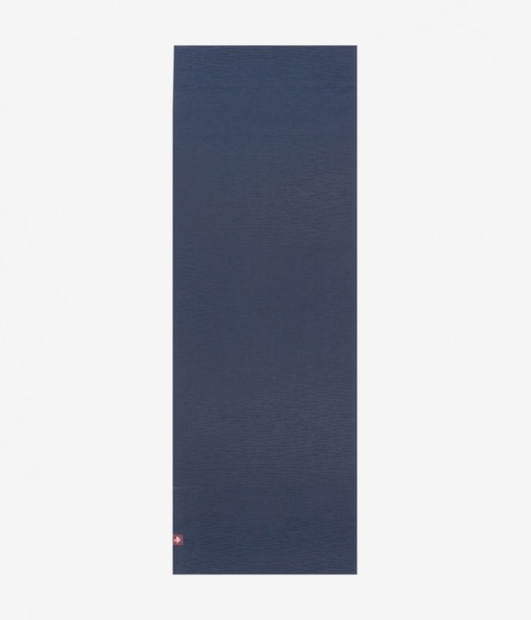 Manduka brand natural rubber 4mm yoga mat in midnight blue; shown unrolled