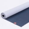 Manduka brand natural rubber 4mm yoga mat in midnight blue; partially unrolled to show both sides of mat