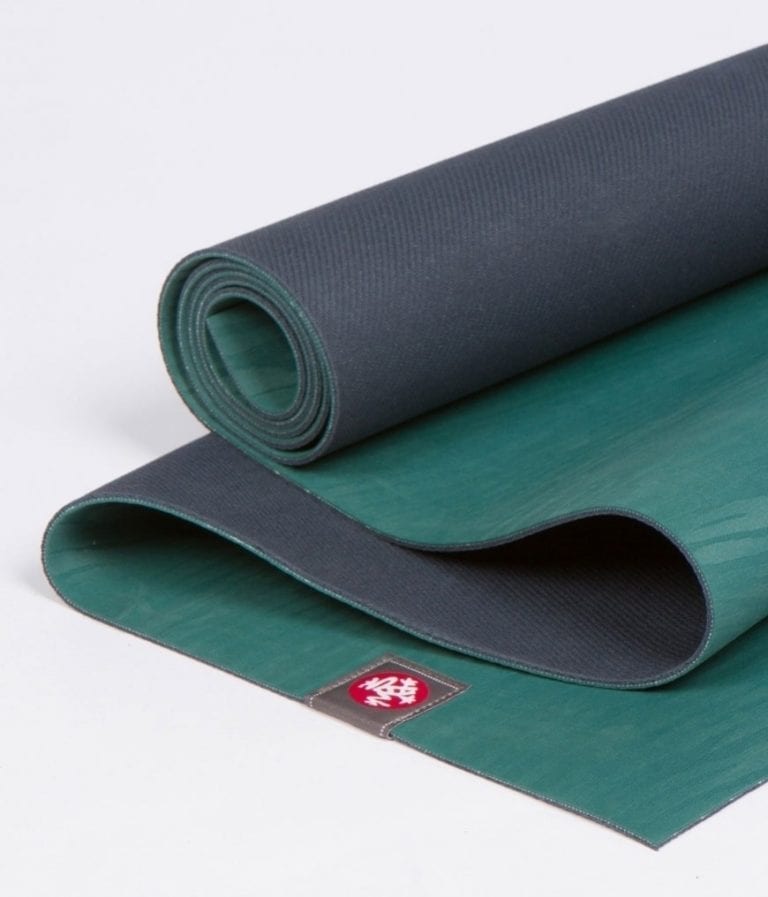 Manduka brand natural rubber 4mm yoga mat in sage/green; partially unrolled to show both sides of mat