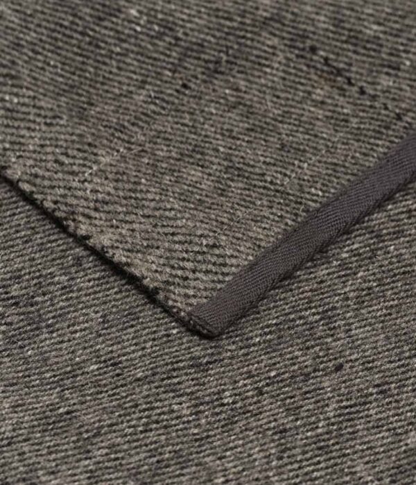 Close-up of binding of Manduka brand wool blanket in sediment gray; made with 100% recycled fibers