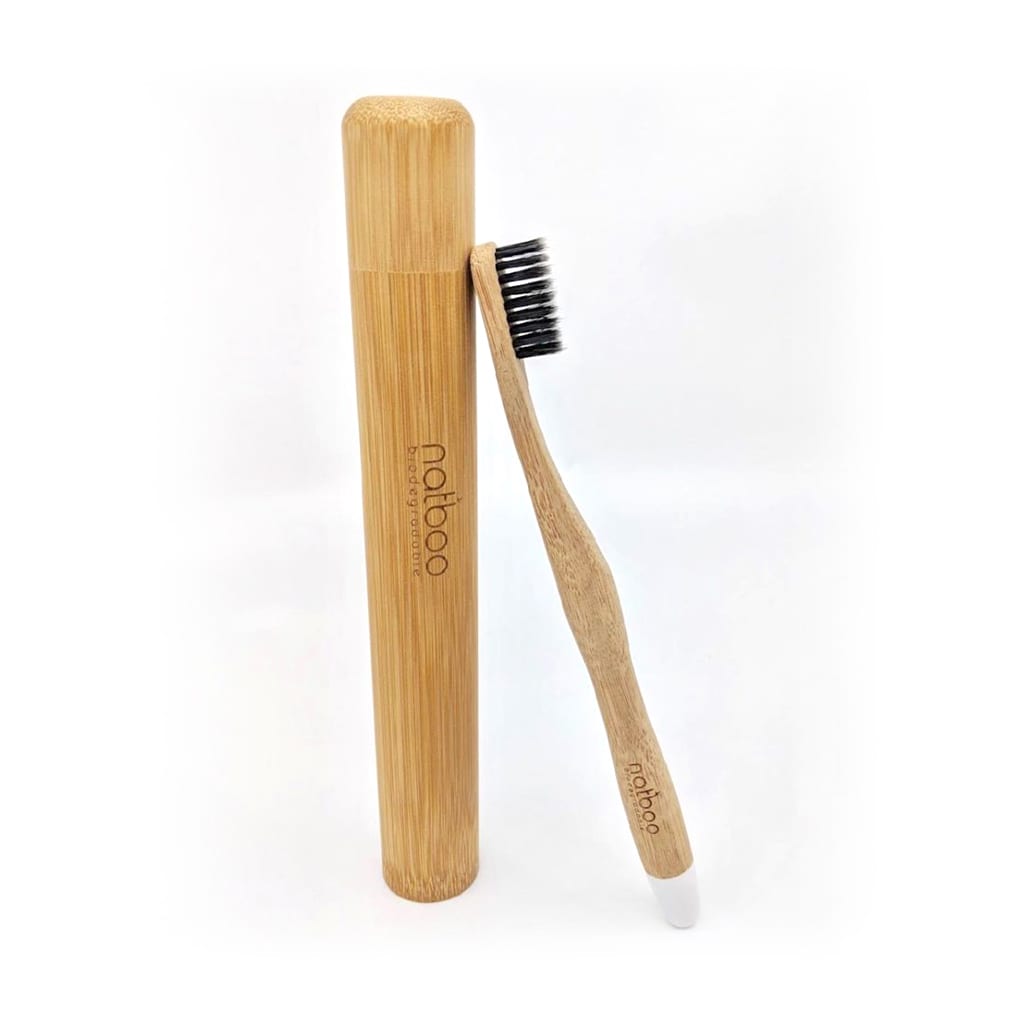 Earth friendly Natboo brand biodegradable bamboo toothbrush with white tip leaning against bamboo Natboo brand oval travel case.  Sold together as Travel set.