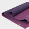 Manduka brand natural rubber 4mm yoga mat in acai purple; partially unrolled to show both sides of mat