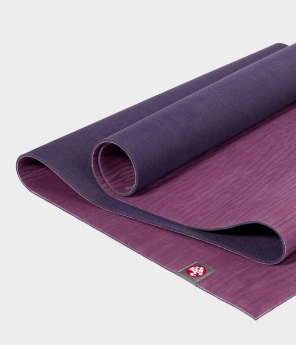 Manduka brand natural rubber 4mm yoga mat in acai purple; partially unrolled to show both sides of mat
