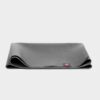 Manduka brand natural rubber 1.5mm travel yoga mat in charcoal gray; folded to show thinness of mat