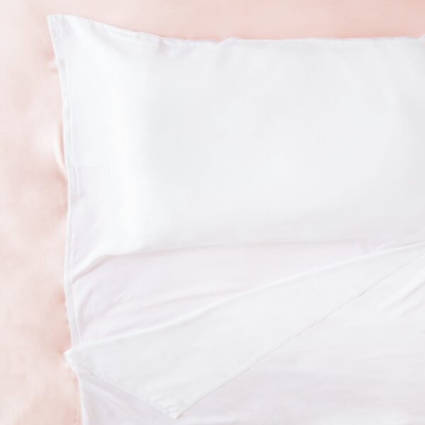 Sustainable organic bamboo white travel sheet spread out on bed, made by Ettitude brand.