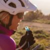 Female mountain biker fueling up on the trial with liquid from her reusable Hydrapak brand durable shape shift 2 liter clear hydration reservoir.