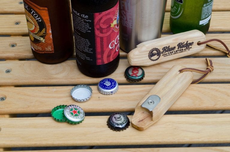 Two eco friendly Blue Ridge Chairs brand American Ash upcycled cap lifter bottle opener with six bottle caps and beer bottles all on foldable Carolina snack table.