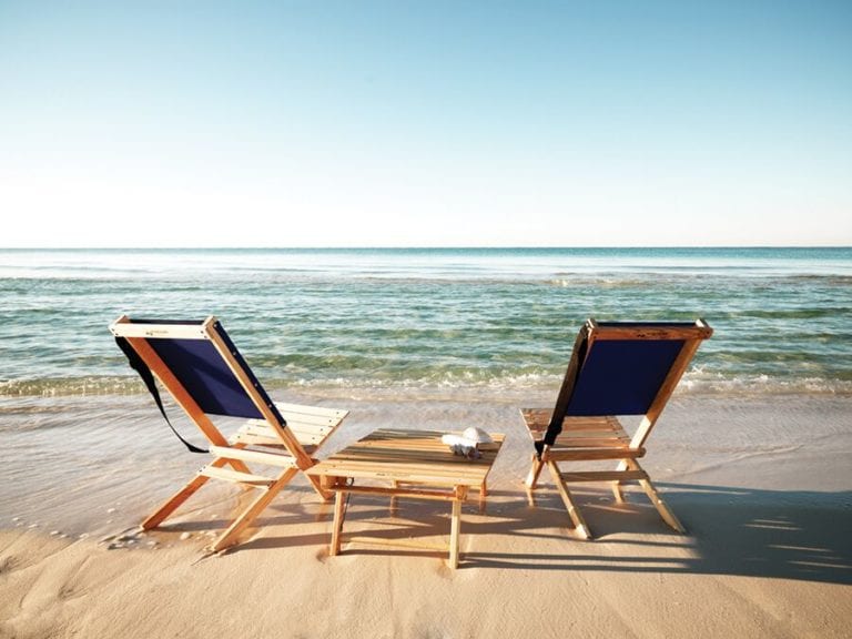 Product display for two eco friendly Blue Ridge Chairs brand American ash Blue Ridge navy blue camping chairs with a Blue Ridge Carolina snack table between them pictured in the sand looking out into the ocean.