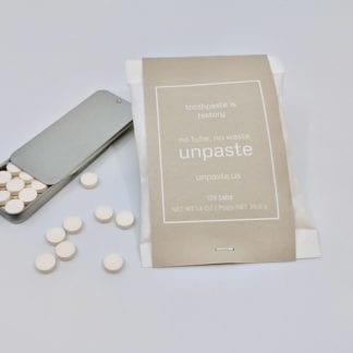 Zero-Waste Toothpaste tablets displayed below a sustainable reusable tin container next to large compostable bag of toothpaste tablets, made by Unpaste brand.