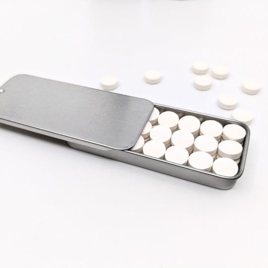Plastic free toothpaste tablets in a travel slider tin