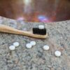 Close up of plastic-free toothpaste tablets with bamboo toothbrush