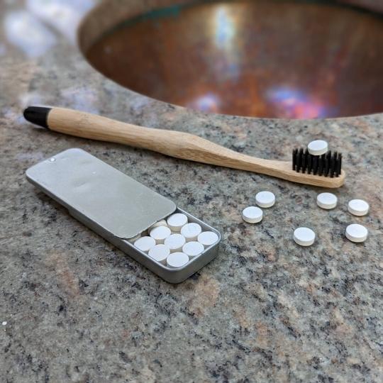 Plastic free eco-friendly dental care with bamboo toothbrush and toothpaste tablets with slider tin