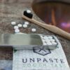 Close up of Unpaste toothpaste tablets with fluoride, bamboo toothbrush and travel slider tin