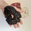 Holding an earth friendly Anchal brand charcoal scrunchie in hand, made from fair trade organic cotton with a bone and rust colored scrunchies pictured below. Sold together in 3 pack.