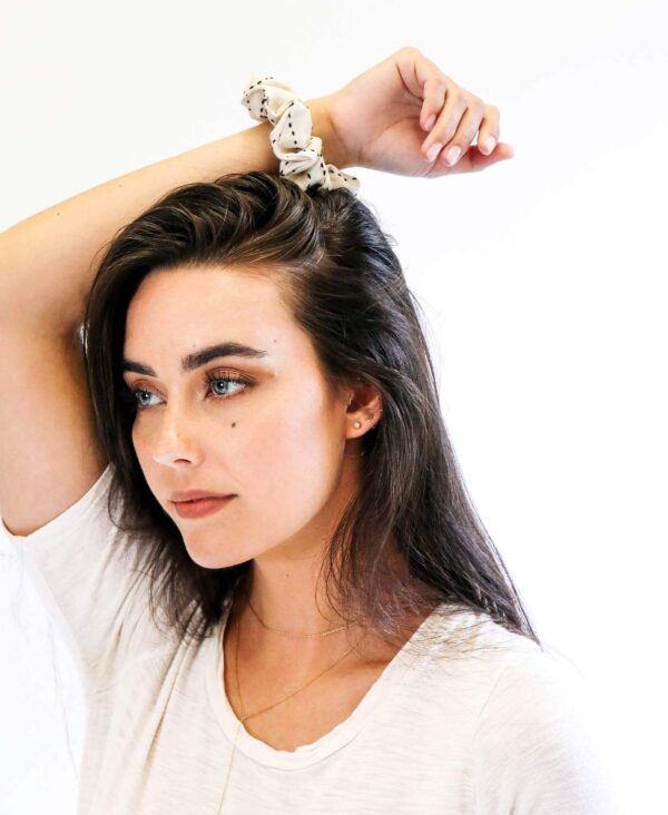 Female modeling Anchal brand fair trade organic cotton bone scrunchie on wrist with arm resting on head.