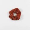 Overhead product display of environmentally friendly fair trade organic cotton Anchal brand scrunchie rust color.