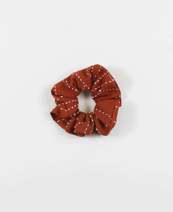 Overhead product display of environmentally friendly fair trade organic cotton Anchal brand scrunchie rust color.