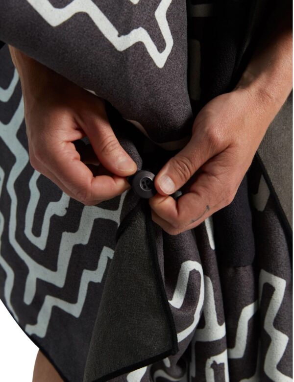 Hands buttoning side of eco-friendly Teton Black Poncho Towel and Blanket for swim, pool, beach, jacuzzi and more.