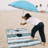Man at beach putting umbrella into hood hole of eco-friendly Baja Aqua Poncho Towel
