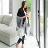 Woman wearing eco-friendly, organic cotton travel blanket cape from Zestt Organics in black and grey colorblock