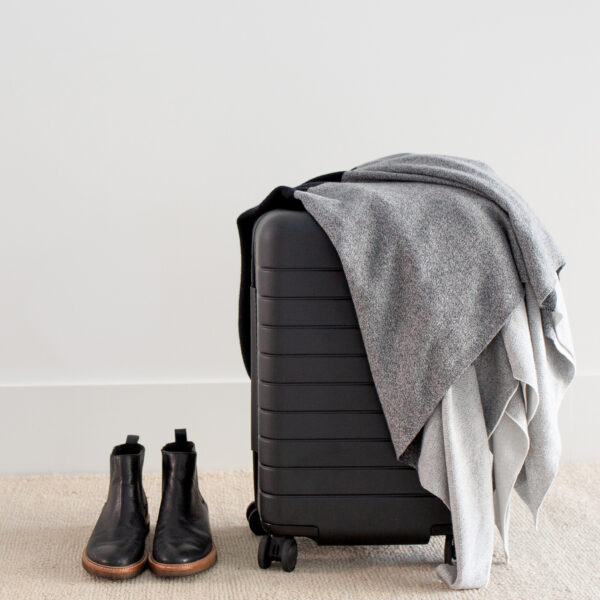 Organic cotton travel cape draped over suitcase for sustainable travel