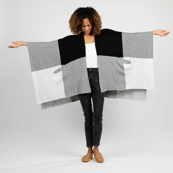 Woman showing full arms outstretched view of organic cotton, one size travel wrap in black and grey colorblock