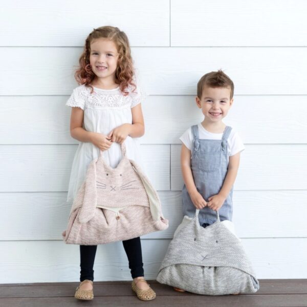 Children modeling their travel blankets. These blankets roll up and have a handle and luggage strap to make them easy to transport on your next trip.