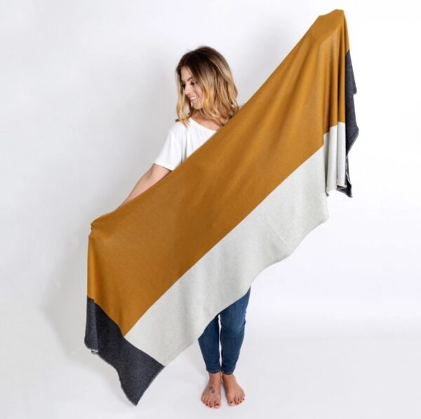 Woman standing against a white backdrop wearing her Organic Cotton Travel Scarf in bronze colorblock, by Zestt Organics