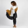 Woman standing against a white backdrop wearing her Organic Cotton Travel Shawl in bronze colorblock, by Zestt Organics