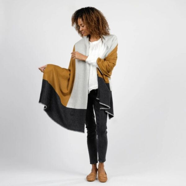 Woman standing against a white backdrop wearing her Organic Cotton Travel Shawl in bronze colorblock, by Zestt Organics