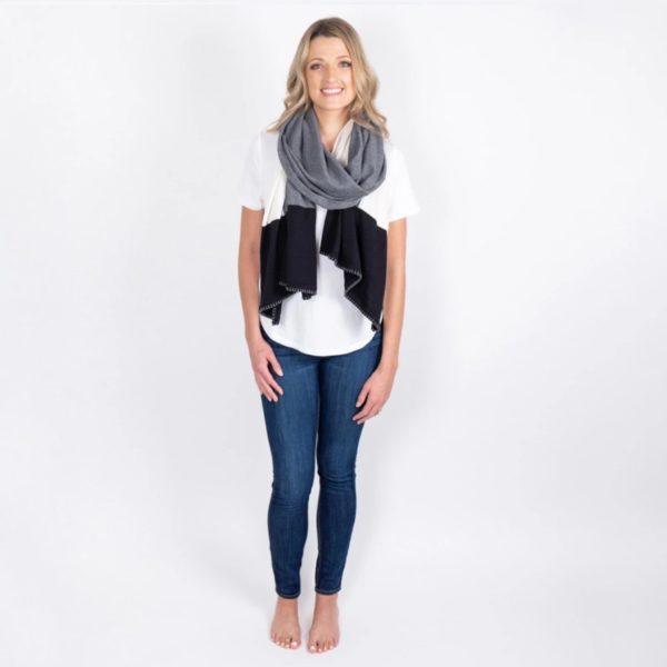 Woman standing against a white backdrop wearing her Organic Cotton Travel Scarf in gray colorblock. Certified organic cotton is environmentally friendly.