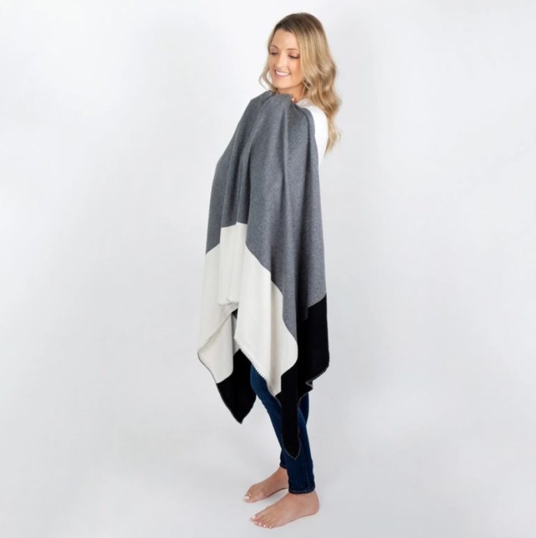 Woman standing against a white backdrop wearing her Organic Cotton Travel Shawl in gray colorblock. Certified organic cotton does not use harsh chemicals or pesticides.