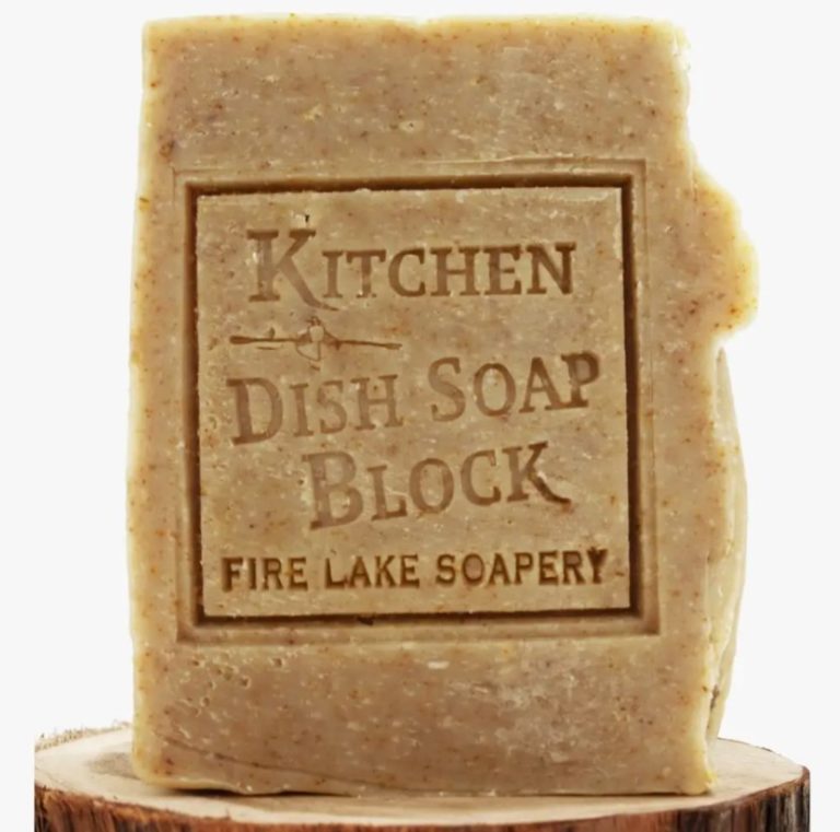 A solid block of eco-friendly dish soap sitting on a tree stump; made by Fire Lake Soapery.