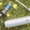 Stainless steel earth-friendly Mizu water bottle with everyday filter is lying in the grass.