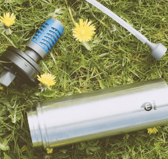 Stainless steel earth-friendly Mizu water bottle with everyday filter is lying in the grass.