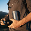 Eco-friendly stainless steel water bottle with every day water filtration insert is being carried on a hike.
