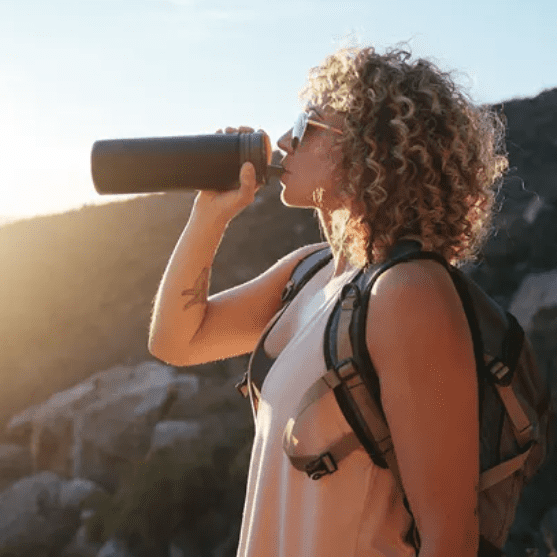 Hiker drinking from sustainable reusable stainless steel water filtration bottle