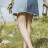 A woman walking through a field with her Mizu stainless steel water bottle and Adventure purifier.