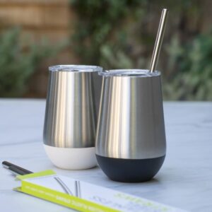 Stainless steel 12 ounce tumblers by UKonserve in two colors, one black and one white. These eco-friendly tumblers are being used at an outdoor cocktail hour.