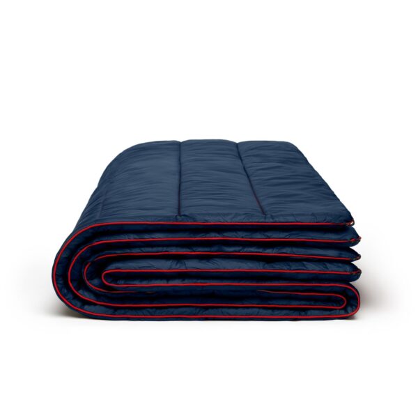 The original puffy 2 person blanket by Rumpl is made from 100% recycled materials. Shown here folded, in deepwater blue with red edging.