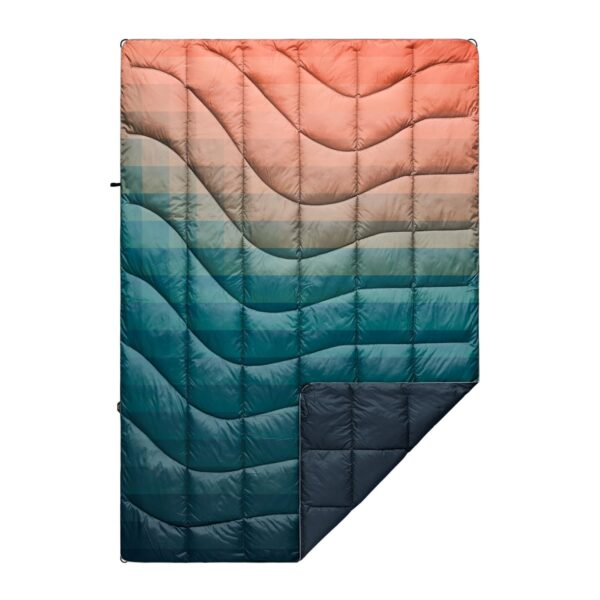 The 100% recycled nanoloft puffy blanket is shown in a patina pixel fade design that fades from pink to blue, a navy backing, and a white binding.